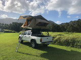 White pickup truck with a rooftop tent, an ideal RV rental for your outdoor mountain adventure.