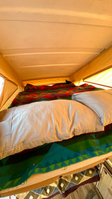 Cozy pop-top bed inside an RV rental, featuring colorful blankets and pillows, ideal for travel adventures.