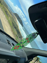 Coastal drive in an rv rental. Beaded car charm overlooks a winding road, cliffs, and ocean.