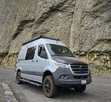 A gray Mercedes Sprinter rv rental, equipped for adventure, parked alongside a magnificent columnar basalt cliff.