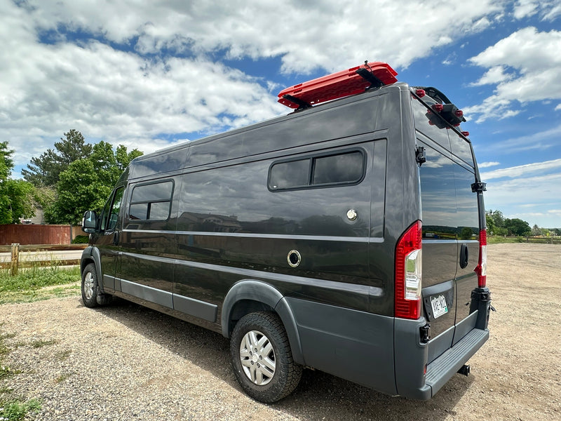 Dark gray camper van, equipped with roof recovery boards & rear ladder, ideal for RV rental adventures. Parked on gravel. — photo 19