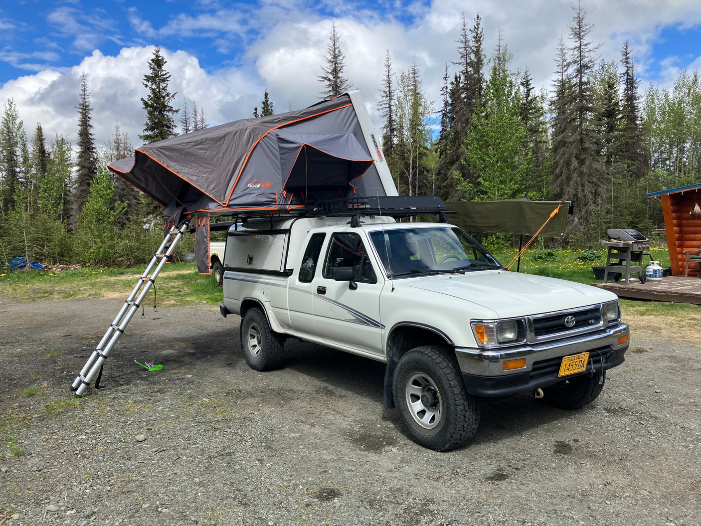 White pickup truck with a deployed rooftop tent, offering an RV rental alternative for camping and overlanding in Alaska.