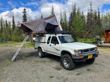 White pickup truck with a deployed rooftop tent, offering an RV rental alternative for camping and overlanding in Alaska.