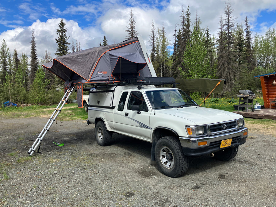 White pickup truck with a deployed rooftop tent, offering an RV rental alternative for camping and overlanding in Alaska.
