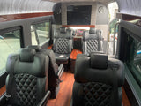 Luxurious RV rental interior: black leather diamond-stitched seats, wood trim, and a large entertainment screen.