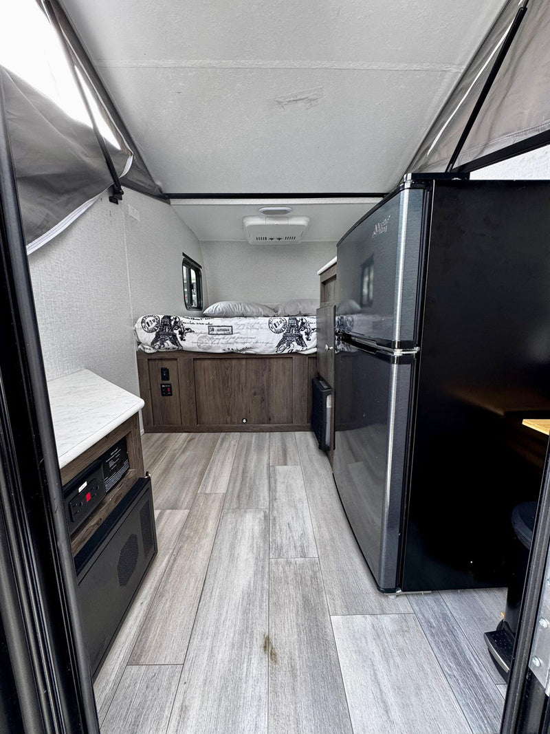  sits on a driveway under cloudy skies.|This rv rental setup features a gray Viking pop-up camping trailer and a Jeep Gladiator — photo 12