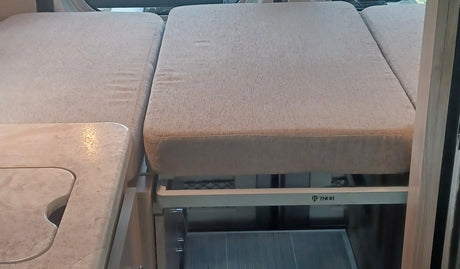 This Thor RV rental interior features a comfortable sleeping area/sofa and a compact kitchen countertop with sink.