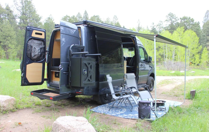 **RV rental** van parked with an extended awning, chairs, and fire pit for a cozy outdoor camping setup. — photo 6