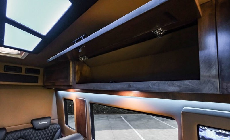 Interior of an RV rental: open overhead storage, skylights, ambient lighting, and large windows revealing the outside. — photo 16
