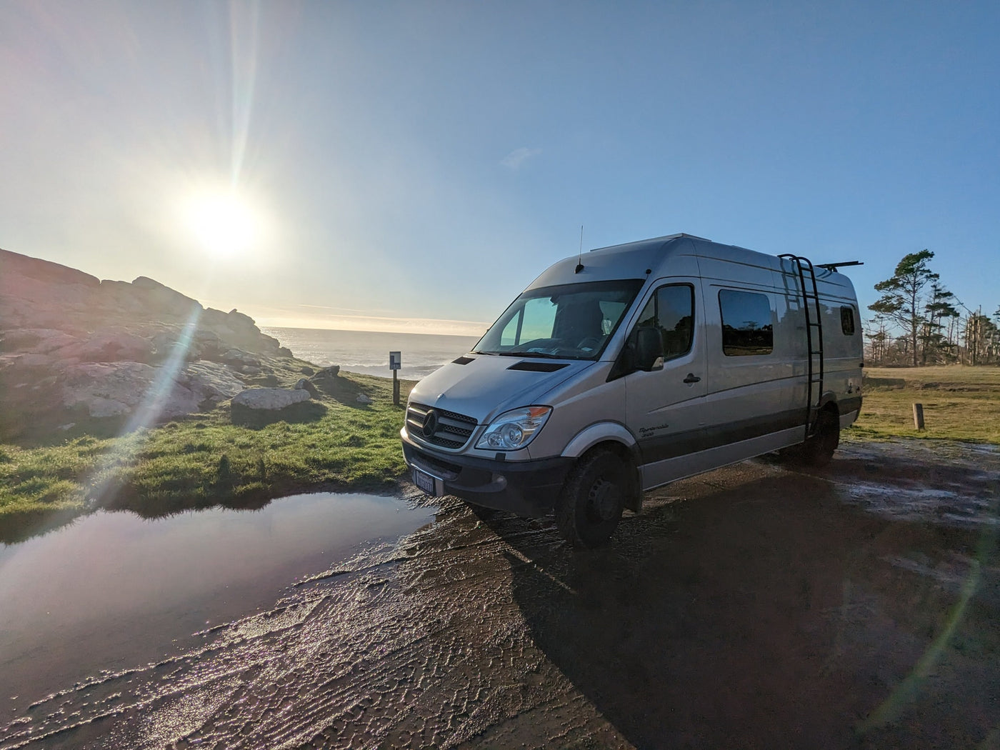  rounded rock formations and desert plants.|Silver Sprinter RV rental at a scenic campsite. A red pop-up tent covers a picnic table where a person enjoys a meal — photo 6
