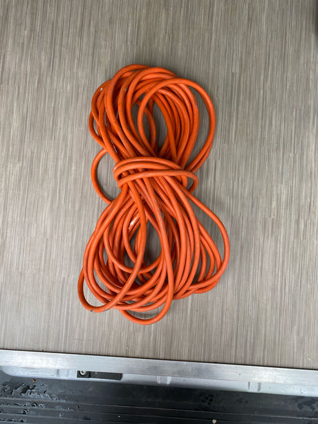 Orange extension cord coiled on an RV floor, ready for your RV rental adventure.