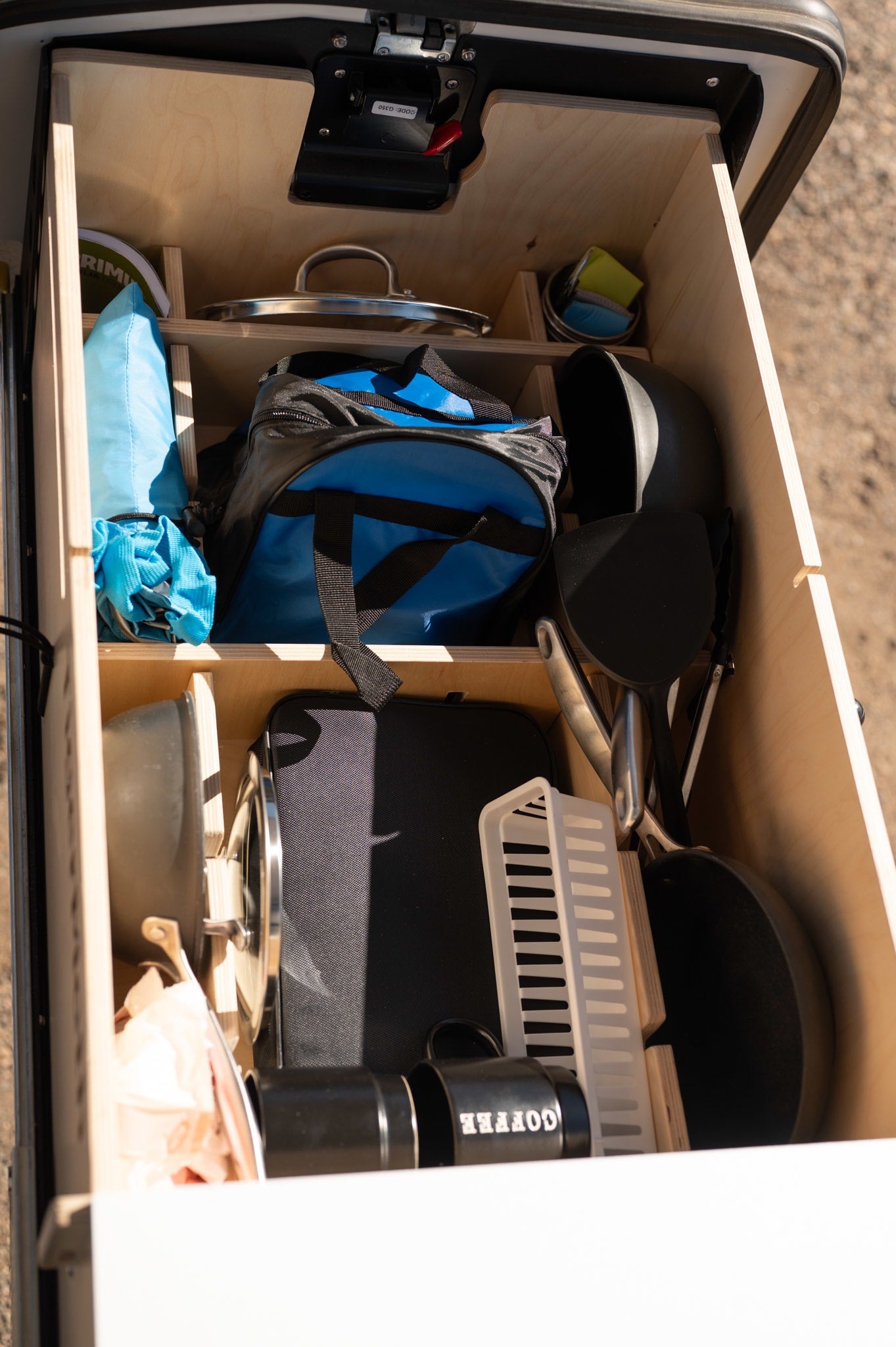 Inside an RV rental: a well-organized pull-out drawer with pots, pans, coffee mugs, and other camping kitchen essentials.