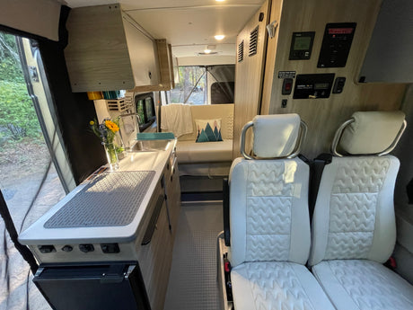 Inside a modern RV rental: well-equipped kitchen, comfortable seating, and tech controls for on-the-go living.