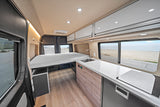 Modern RV rental interior featuring a comfortable bed, full kitchen, and scenic ocean view for your next adventure.