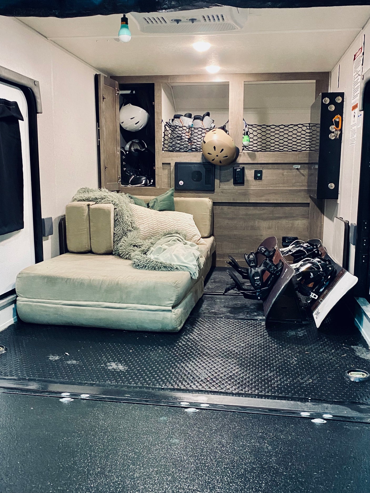 Cozy RV rental interior: A toy hauler with a comfortable lounge area and organized snowboarding gear, perfect for adventure travel.