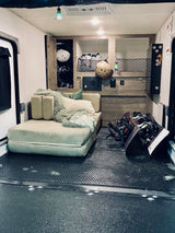 Cozy RV rental interior: A toy hauler with a comfortable lounge area and organized snowboarding gear, perfect for adventure travel.