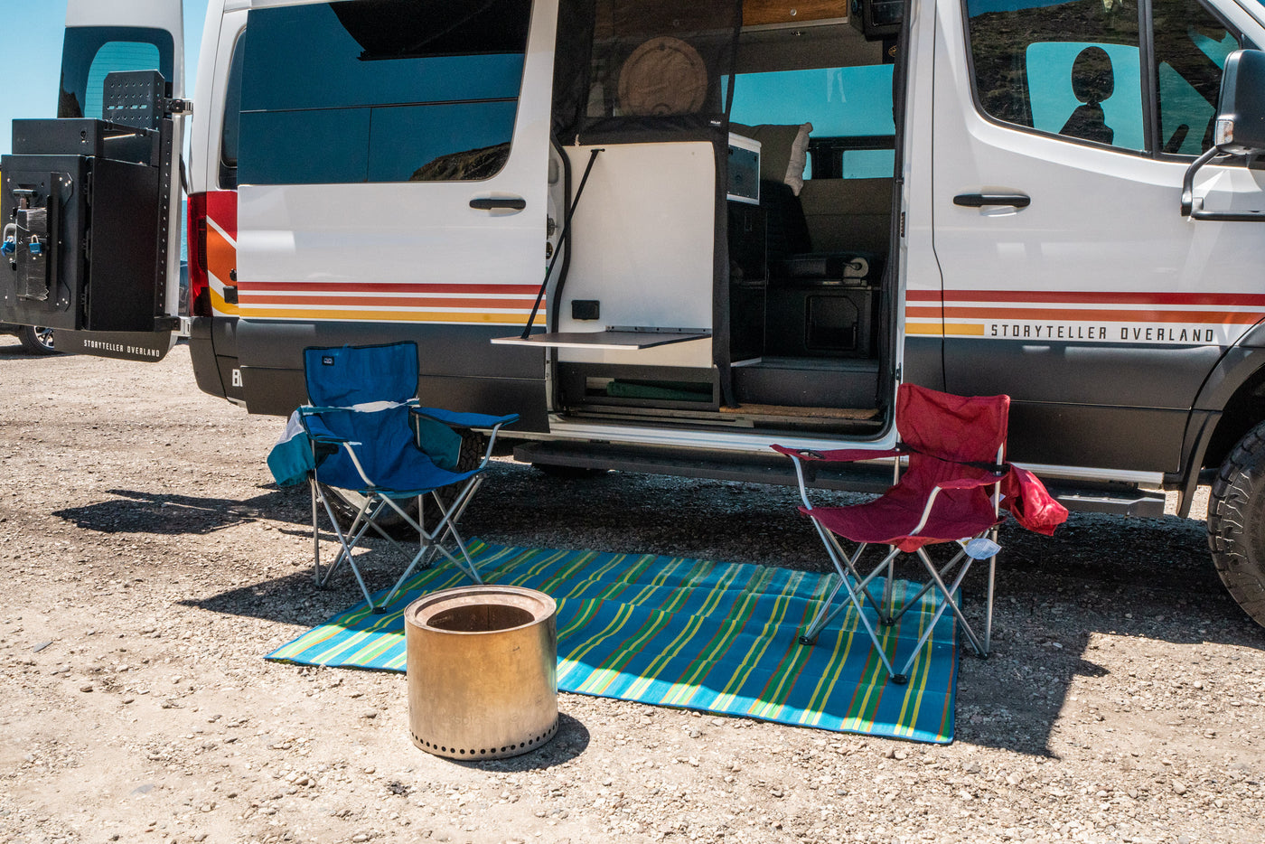 A Storyteller Overland camper van, perfect for RV rental adventures, with an outdoor setup including chairs, mat, and Solo Stove. — photo 8