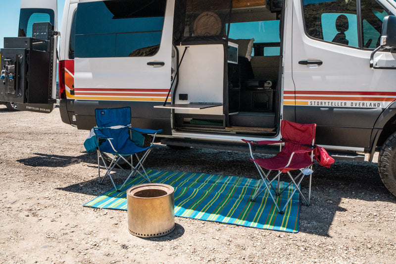 A Storyteller Overland camper van, perfect for RV rental adventures, with an outdoor setup including chairs, mat, and Solo Stove. — photo 8