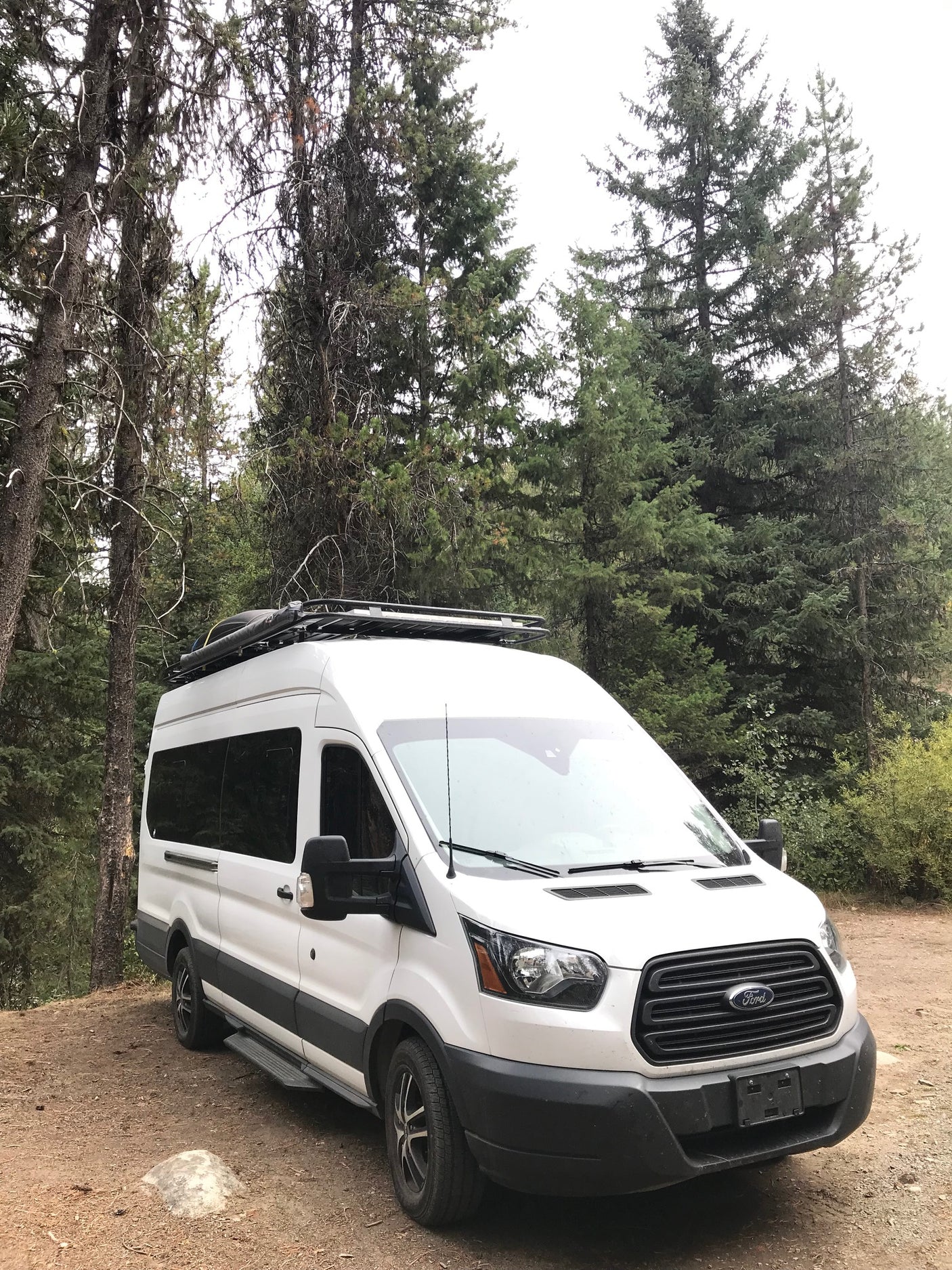 White Ford Transit RV rental van, perfect for forest camping & outdoor adventures.
