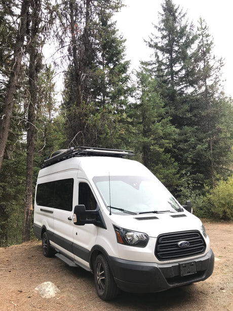 White Ford Transit RV rental van, perfect for forest camping & outdoor adventures.