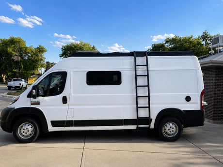 White camper van with a black side ladder and roof rack, parked outdoors. Ideal for your next rv rental adventure.