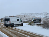 White RV rental parked on a snow-covered dirt road at Agua Fria National Monument during winter.