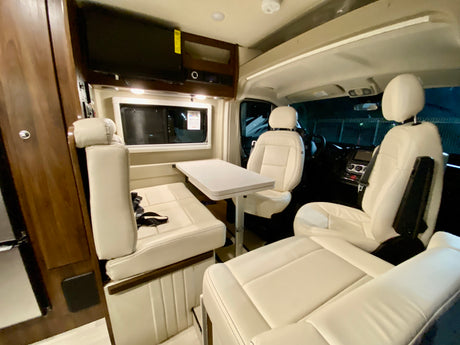 Spacious RV rental interior with cream seating, dinette, and TV, perfect for comfortable road trips.