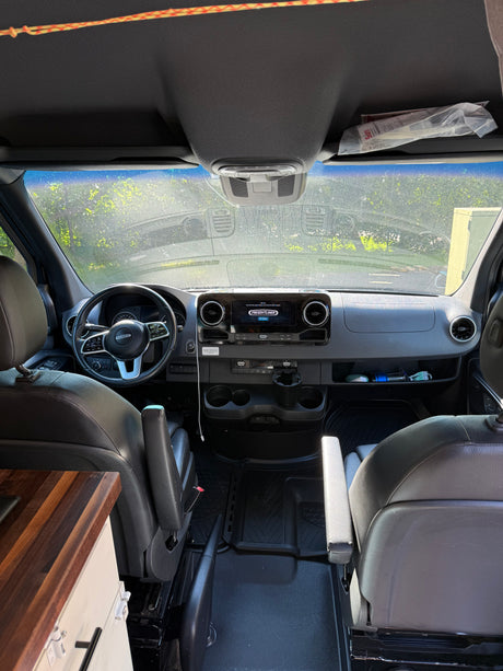 Modern Freightliner RV rental van interior, showing dashboard, steering wheel, and front cabin with living area details.