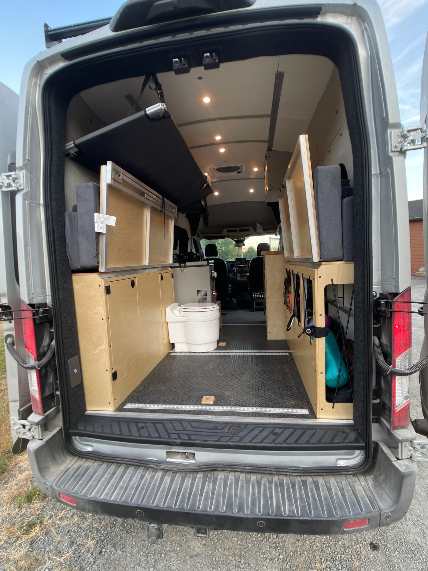 Inside this RV rental: versatile van interior with a folded bed, storage units, and a portable toilet. — photo 7