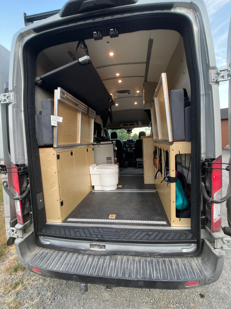 Inside this RV rental: versatile van interior with a folded bed, storage units, and a portable toilet. — photo 7