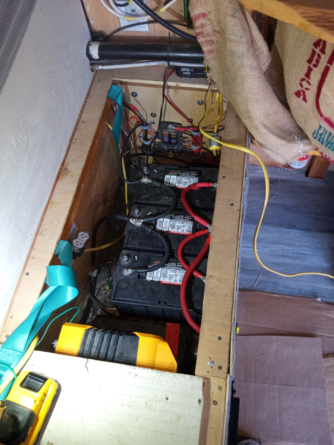 RV rental setup: Three Duracell batteries, wiring, fuse block, NOCO charger, and inverter for vehicle power.
