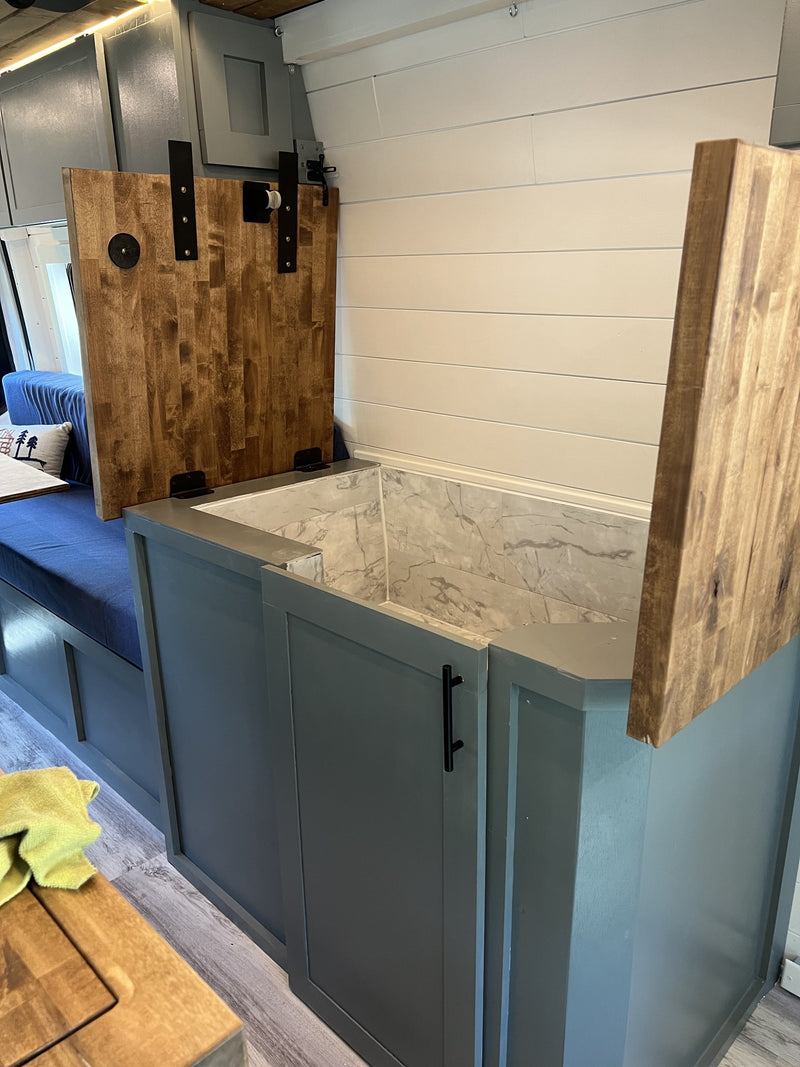  with green view outside.|Bright and modern RV rental interior featuring a full kitchen with wood counters — photo 16