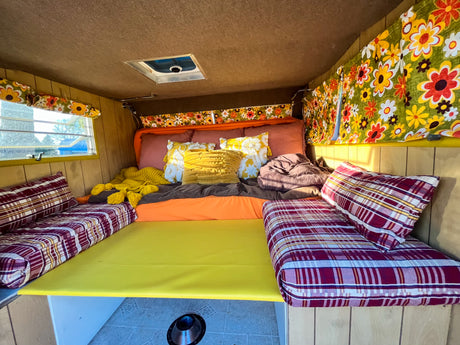Cozy, colorful, retro RV interior with a bed and floral curtains, ready for your next RV rental adventure.