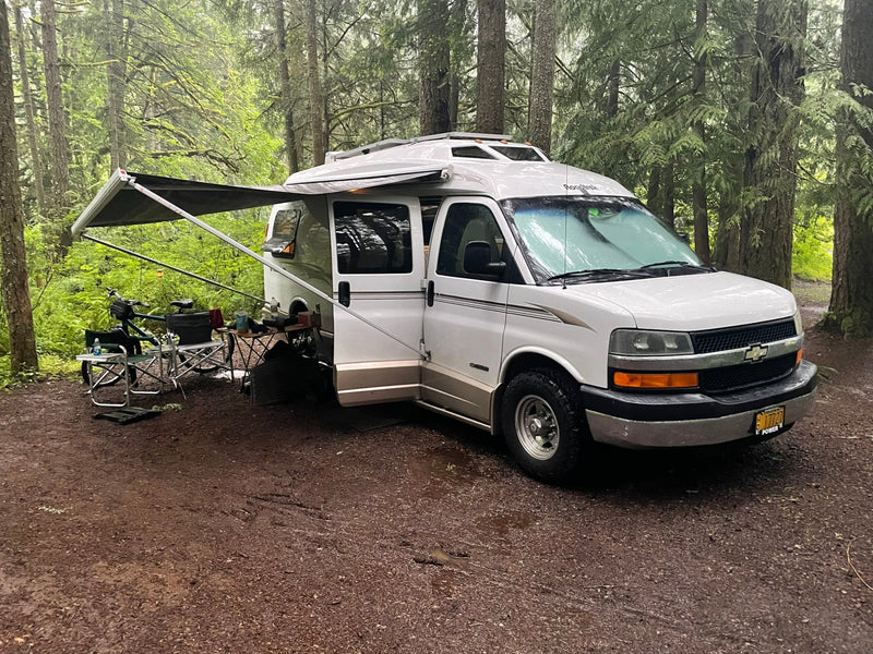  ideal for nature exploration.|A white Roadtrek RV rental is parked with a trailer carrying mini bikes — photo 9