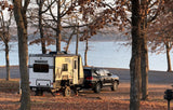 Winnebago Hike RV rental towed by an SUV, parked lakeside under trees with autumn leaves. Ideal for camping.