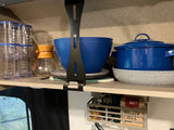 Efficient RV rental kitchen setup: coffee maker, blue pot & bowls, stacked tumblers, and under-shelf spice rack.