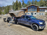 Explore the outdoors with this **RV rental** alternative: a Toyota Tundra overland truck and rooftop tent setup in a scenic mountain setting.