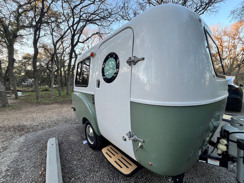 Charming green & white retro-style RV rental parked in a wooded campsite, ideal for travel and camping adventures. — photo 12