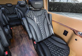Plush black leather seating inside a luxury RV rental, featuring diamond stitching, wood flooring, power outlets, and cup holders.
