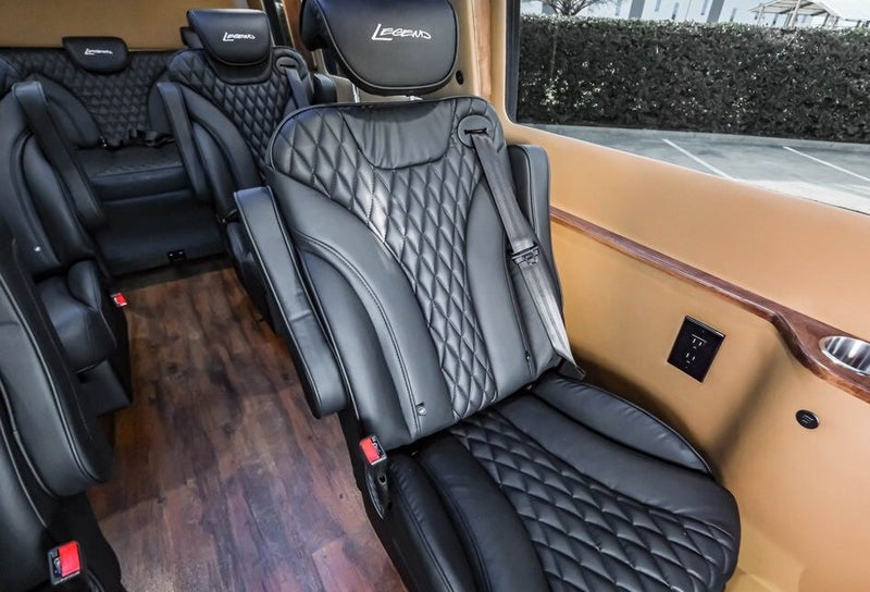 Plush black leather seating inside a luxury RV rental, featuring diamond stitching, wood flooring, power outlets, and cup holders. — photo 14