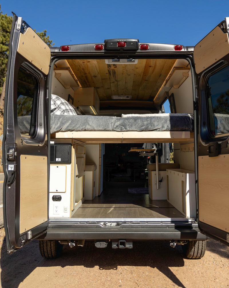 Rear view of an open RV rental camper van, showing a cozy elevated bed, wood ceiling, and built-in storage for travel adventures. — photo 8