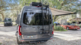 Experience adventure with this gray Winnebago Revel 4x4 Sprinter camper van rental, parked outdoors with another van nearby.