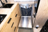 Compact RV rental interior: integrated kitchen with stovetop & sink, plus a clever pull-out shower system for efficient van life.