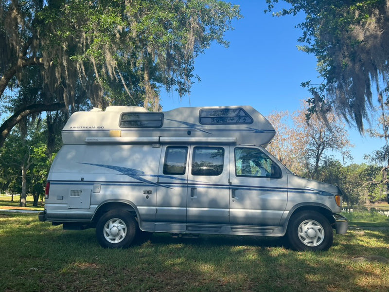 Silver Airstream 190 camper van, a perfect RV rental for exploring outdoors. Parked by a lake under mossy trees. — photo 2