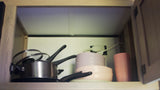 RV rental kitchen: pots, pans, and durable dishes stored in a cabinet with an outlet.