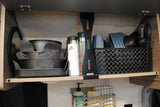 Inside an RV rental: organized kitchen cabinet with stackable cookware, Stanley thermoses, cups, and utensils.