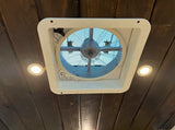 RV rental interior ceiling with a white vent fan, two bright LED lights, and rustic dark wood paneling.