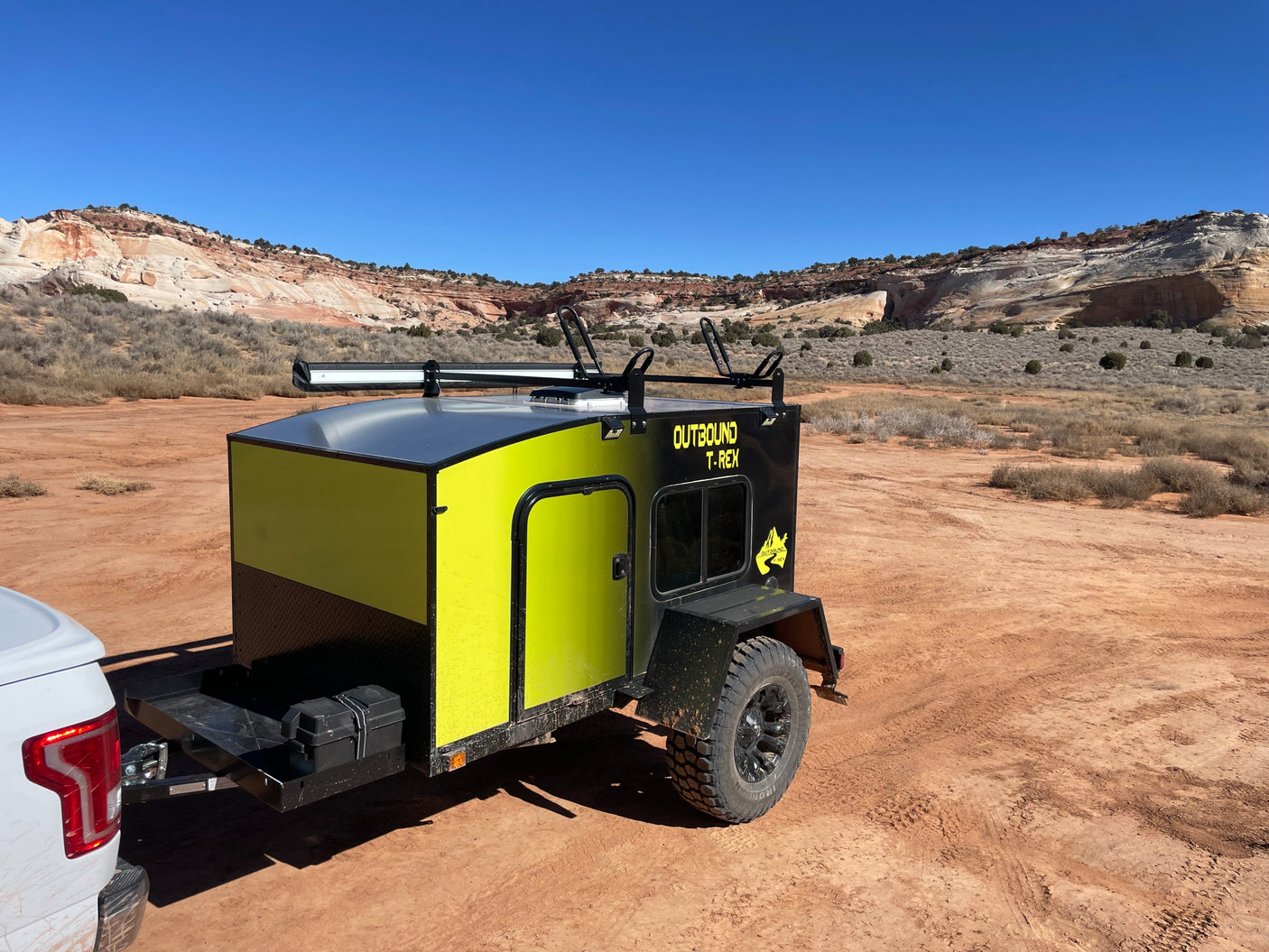 Adventure awaits! This Outbound T-Rex off-road trailer, available as an RV rental, is set in a stunning desert landscape.