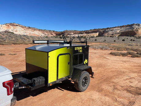 Adventure awaits! This Outbound T-Rex off-road trailer, available as an RV rental, is set in a stunning desert landscape.