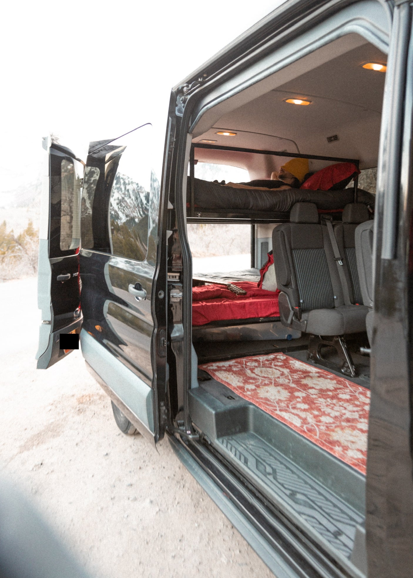 Step inside this RV rental: a spacious camper van with bunk beds, passenger seats, and a cozy setup for your travels.